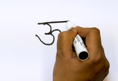 A hand writing down a Devanagari mark