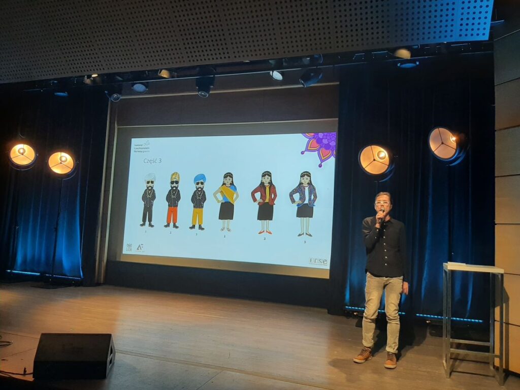 Łukasz Pelc z Grupy AF opowiada o aspektach technicznych powstania platformy. Na slajdzie prezentuje wybrane grafiki stworzone przez grafików z Grupy AF.